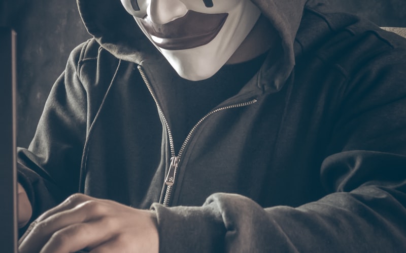 Person mit Maske am Laptop als Symbol für Täuschung und Identitätsmissbrauch bei Social Engineering