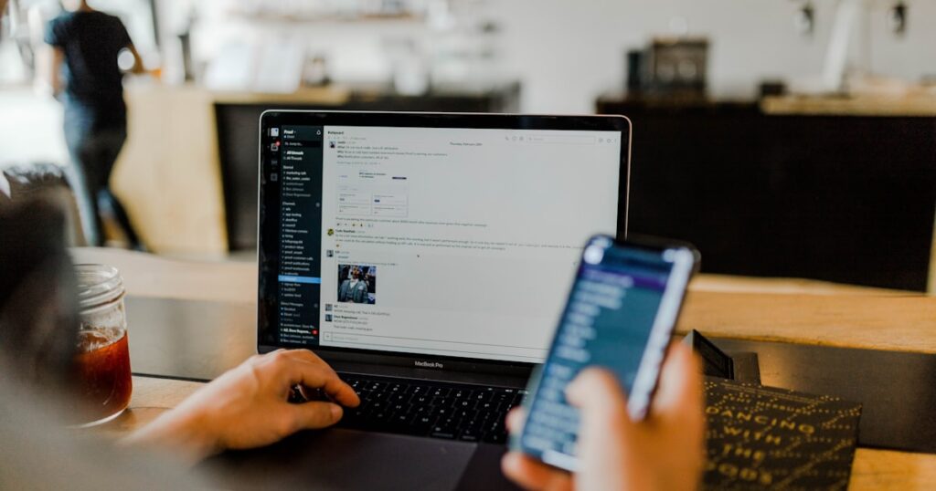 Person nutzt Smartphone und Laptop gleichzeitig – typische Angriffsfläche für Social Engineering