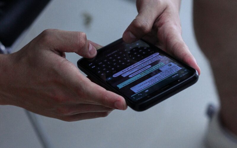 Zwei Personen schauen gemeinsam auf eine Chat-Konversation auf einem Smartphone